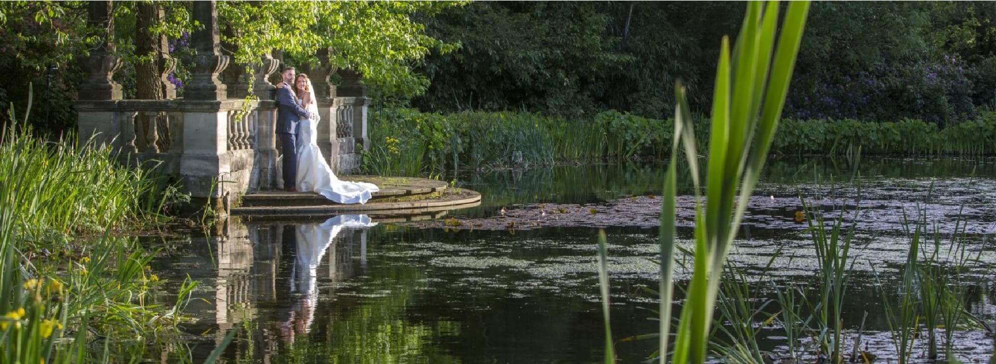 Wedding Photographer Warwickshire: The happy couple by a lake with their reflections in the water