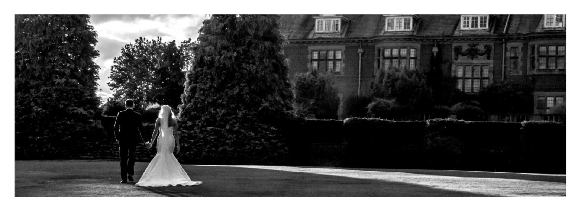 Wedding Photographer Warwickshire at Dunchurch Park: Couple walking through the grounds in evening sun light