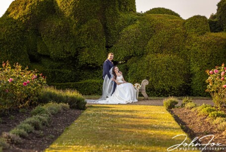Bride and groom by the topiary at Rockingham Castle