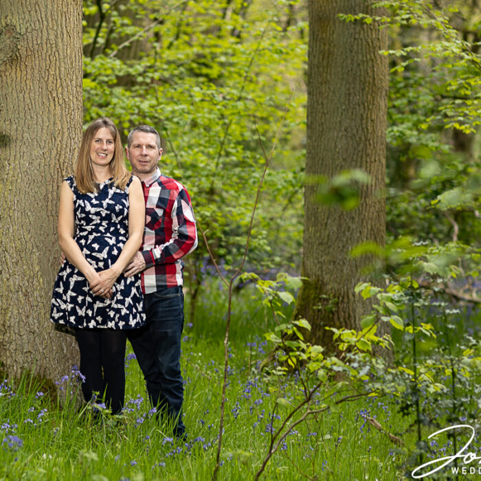 Bride and Groom leaning against a tree on their pre-wedding shoot in woodland in Northamptonshire