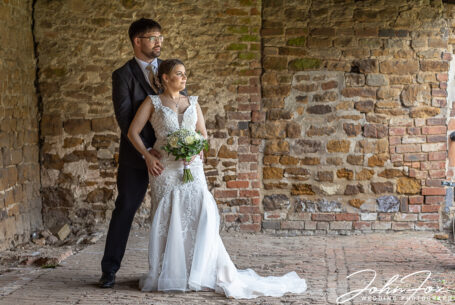 The happy couple standing in a courtyard at The Barns at Hunsbury Hill, Northamptonshire