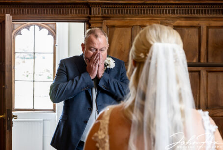 Emotional father of the bride seeing his daughter for the first time in her dress at Ashridge House