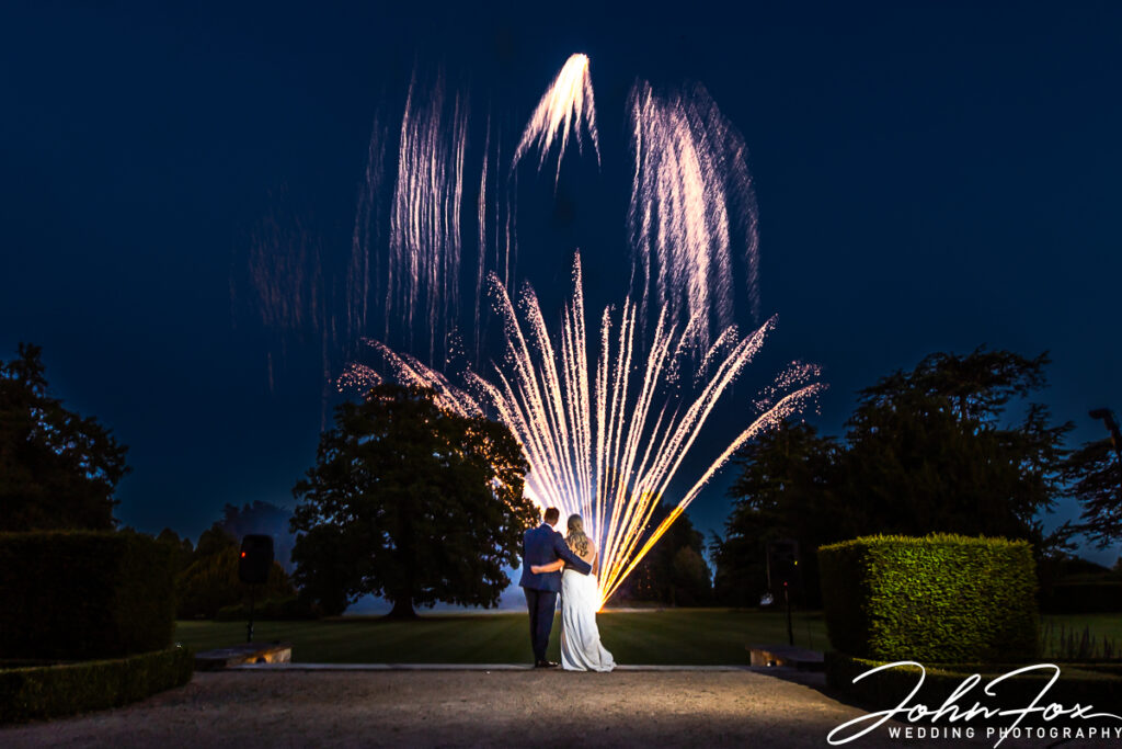 Bride and Groom, Zoe and Joshua, watching fireworks at Ashridge House as part of their wedding day celebrations. Image by John Fox Wedding Photography.
