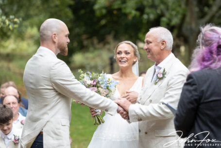 The father of the bride gives his daughter away. Photo by John Fox Wedding Photography