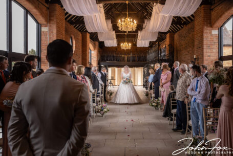 The bride walking up the aisle at Meadow Barn, Stratford-upon-Avon. Image by John Fox.
