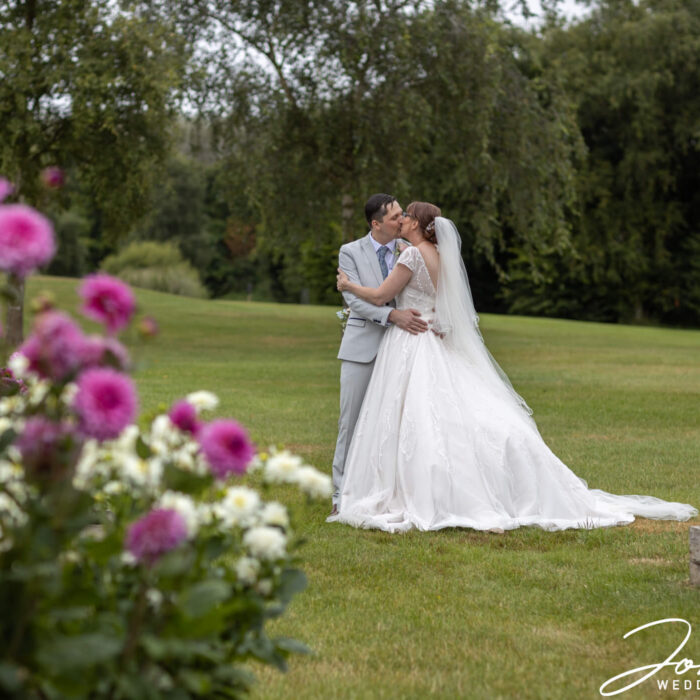 The wedded couple kiss in the grounds at The Stratford Park Hotel