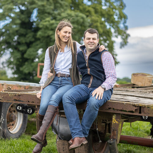 The happy couple sitting on a trailer on their farm