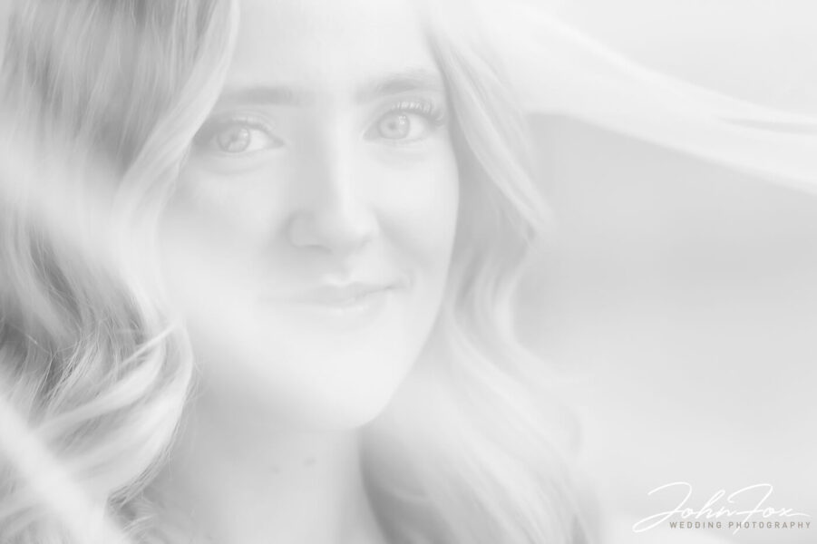 Close-up of Lorna looking straight at the camera through her veil. Photo by John Fox Wedding Photography
