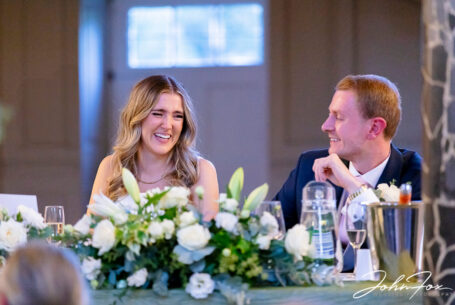 Lorna and James laughing together at the top table during their wedding celebrations at Chicheley Hall.