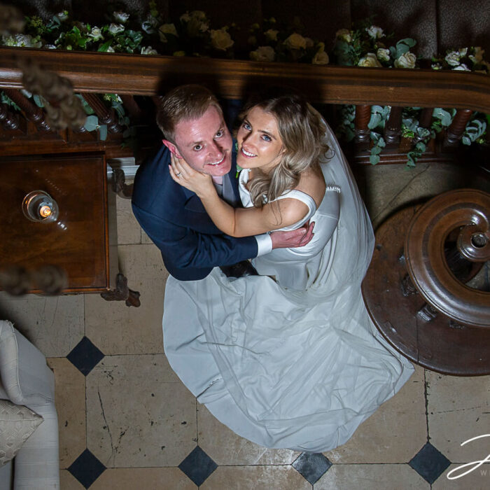 Lorna and James sitting by the grand staircase inside the hall at this wonderful Buckinghamshire wedding venue