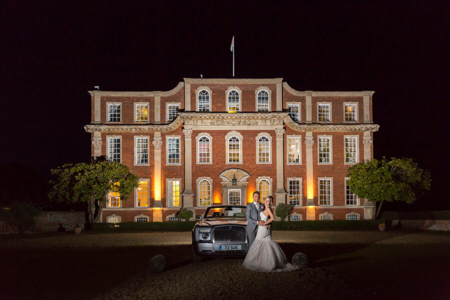 Bride and Groom by the wedding car at night in front of Chicheley Hall