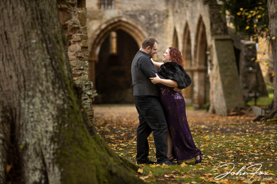 Autumnal Pre-Wedding Shoot with Ettington Park Hotel in the back ground as couple walk along