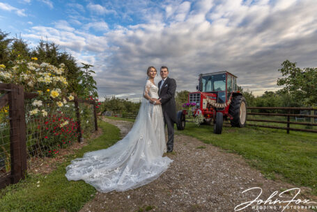 Bride and groom stood by an old tractor on the family farm in Derby.