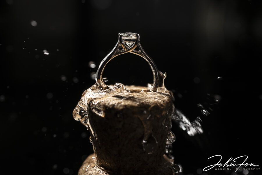 Celebrate a Christmas engagement with a photo shoot. Image of an engagement ring in a champagne cork splashed with champagne.