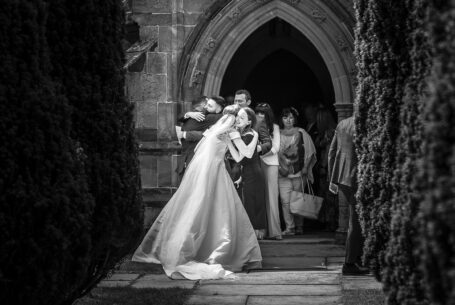 Natural documentary wedding photograph of the bride and groom being congratulated outside the church