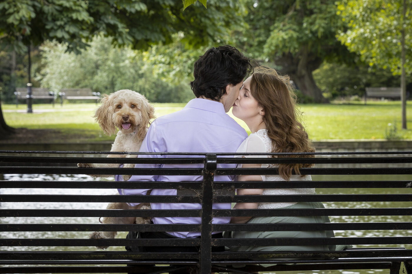 How to choose your wedding photographer. Pre-wedding photo of a couple kissing on a park bench.