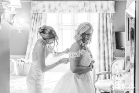 Bridesmaid helping the bride with her wedding dress at Coombe Abbey, Coventry.