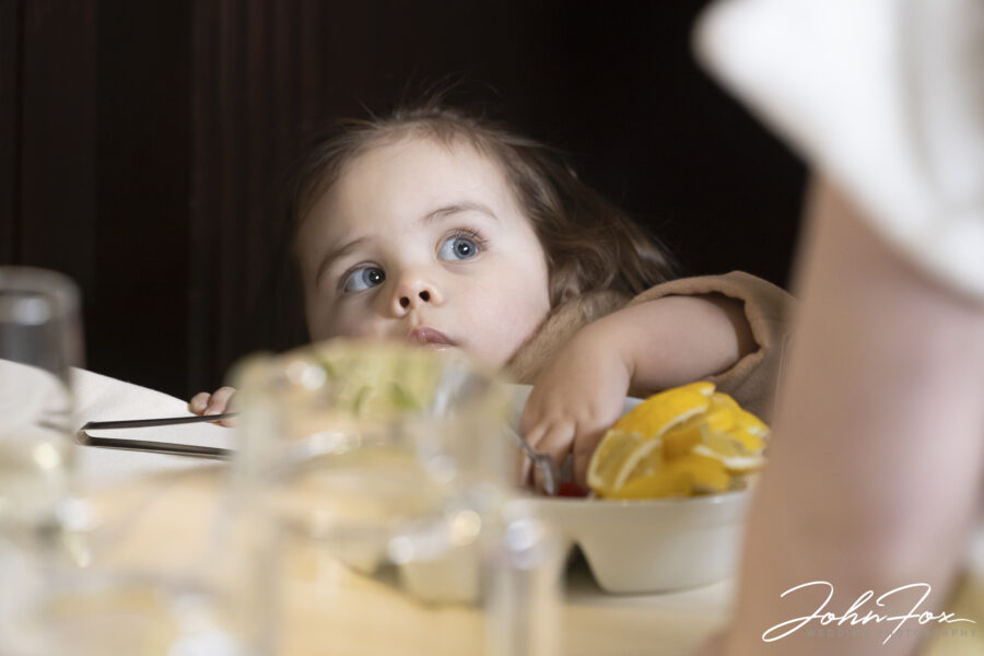 Flower girl sneaking fruit from a bowl at Coombe Abbey, Coventry. John Fox Wedding Photography.