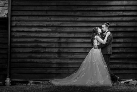 Bride and groom against a dark wood barn at a Venue Group wedding venue