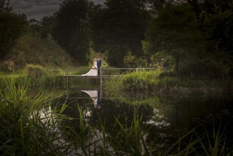 Bride and groom reflected on a lake at The Great Barn, Oxfordshire