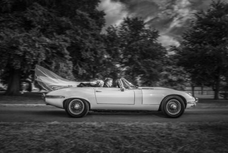 E-type jaguar. Bride and groom in the car with brides veil blowing in the wind