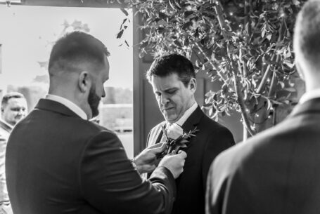Valentine’s Weekend Wedding Photography at Fawsley Hall. Groom and groomsmen adding roses to jacket button holes.