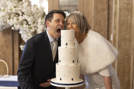 Valentine’s Weekend Wedding Photography at Fawsley Hall. Fun cake image with bride and groom taking a bite