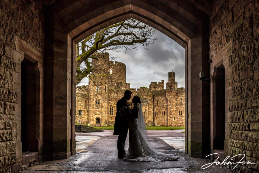 Bride and groom silhouette against Peckforton Castle, Cheshire