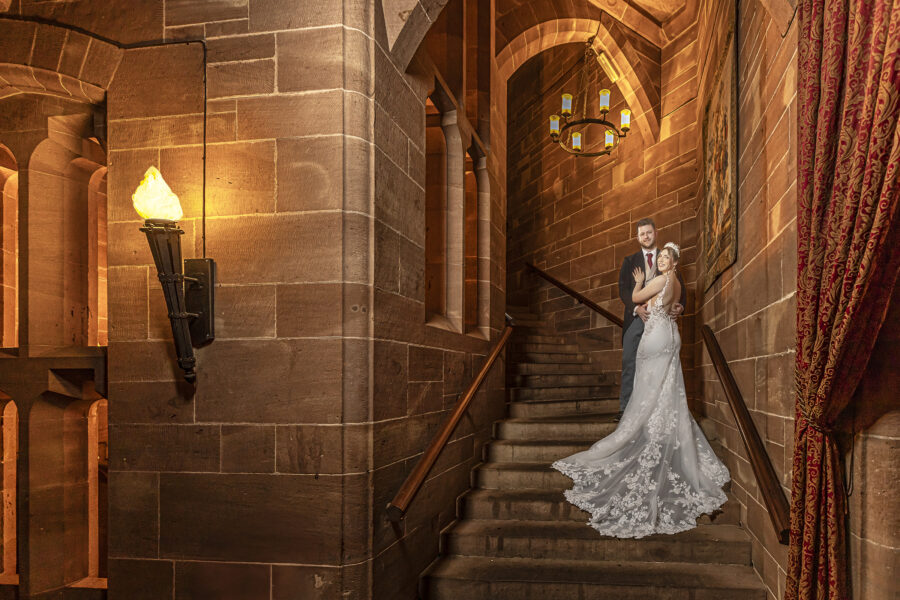 Bride and groom on the stone stairs at Peckforton Castle
