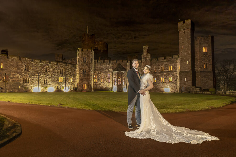 Bride and groom by Peckforton Castle at night