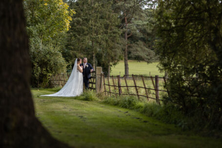 Bride and groom looking out over a 5-bar gate