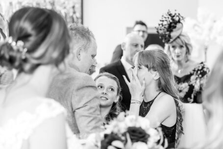 Bridesmaids hugging their father after the wedding ceremony