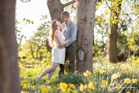 Happy couple on their pre wedding shoot at Ansty Hall in wooded area with spring daffodils