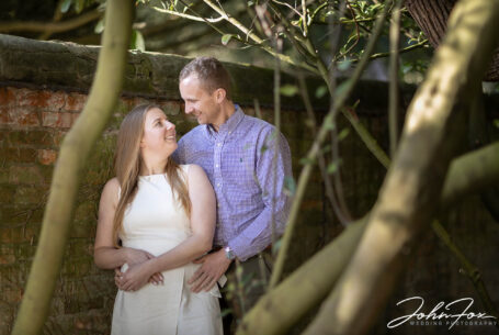 Harriet and Luke on their pre wedding shoot at Ansty Hall in wooded area and garden wall using bounced light