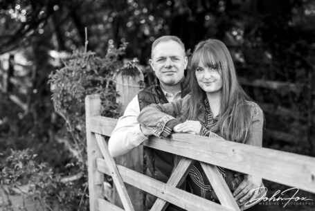 Emma and Lee leaning on a gate on their pre-wedding shoot in Northamptonshire