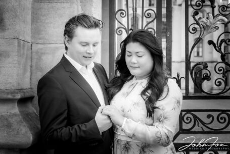 Pre-wedding Shoot in Oxford showing couple by a gate and looking at the engagement ring