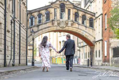 Pre-wedding Shoot in Oxford with the couple walking towards the Bridge of Sighs