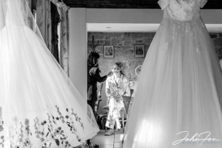 Bridal preparations showing bride having makeup applied and using the wedding dress to frame the image by John Fox Wedding Photography