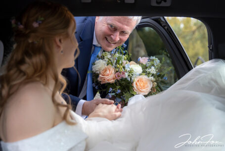 Father of the bride helping bride out the car at a Wiltshire wedding.