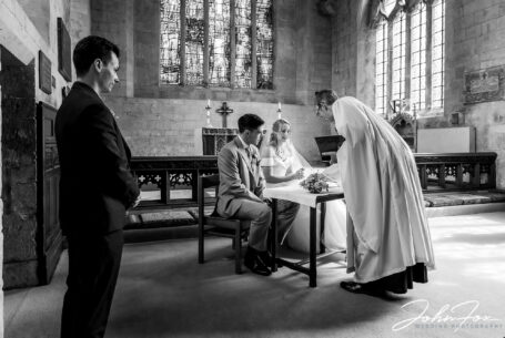 Image of bride and groom with the vicar during the signing of the register