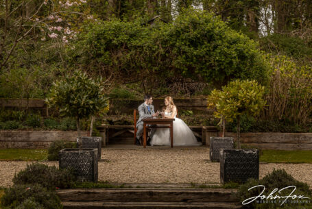 Creative image of bride and groom framed by garden plants