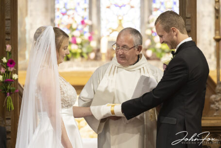 Bride and groom and the vicar during the wedding ceremony at St James' Church