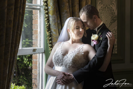 Bride and groom by a window using natural light. John Fox Wedding Photography