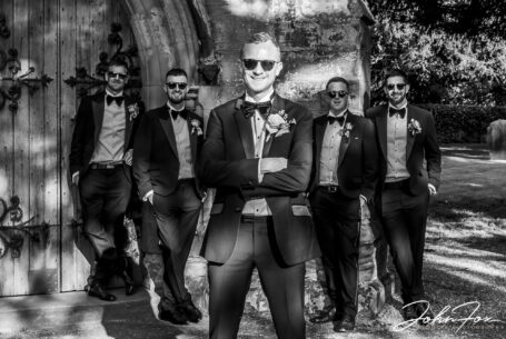 Groom and groomsmen in a boyband style pose outside the church