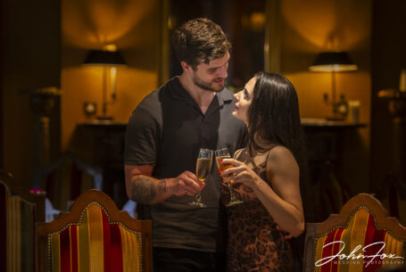 Couple photographed on their pre-wedding shoot indoors, celebrating with some bubbly