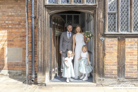 Bride and groom and flower girls in the doorway at Henley Room