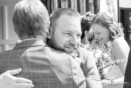 Groom with bride in the background being congratulated. Image by John Fox.
