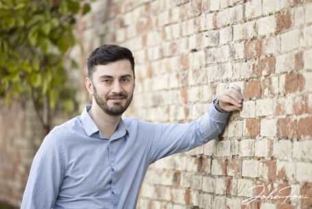 pre-wedding shoot image of the groom leaning casually on a brick wall to add texture. Warwickshire wedding photography