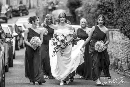 Wedding Photography for Emma and Lee in Leicestershire. Bride walking to church with the bridal party