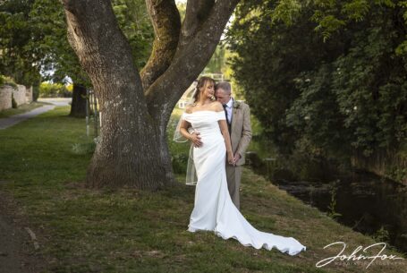 Portrait of the bride and groom by a stream. Wedding Photography for Emma and Lee in Leicestershire